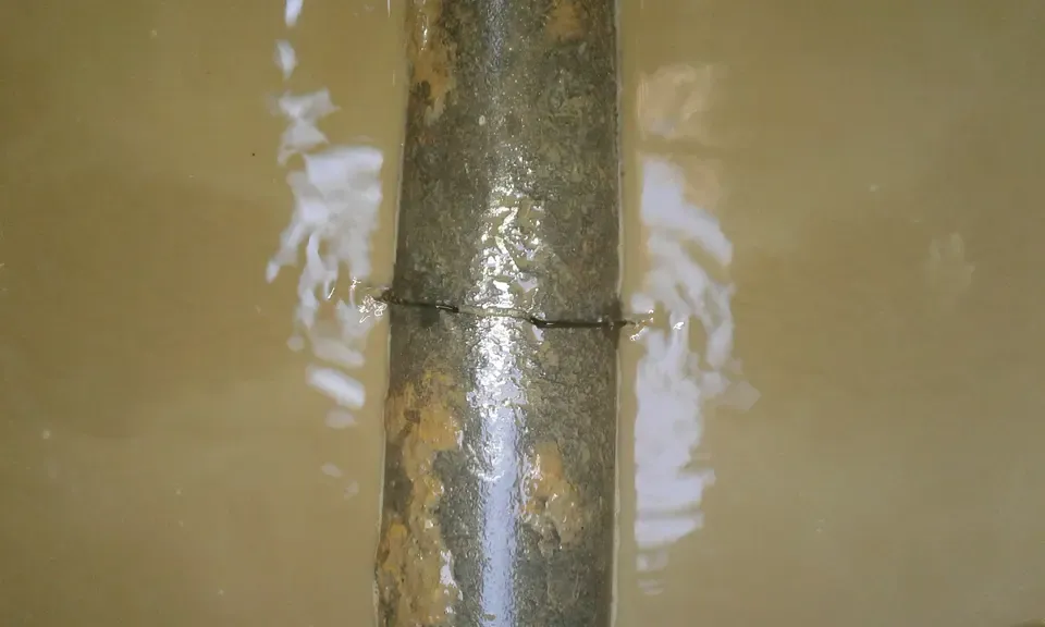 Wasserrohr mit Riss im trüben Wasser, nahaufnahme.