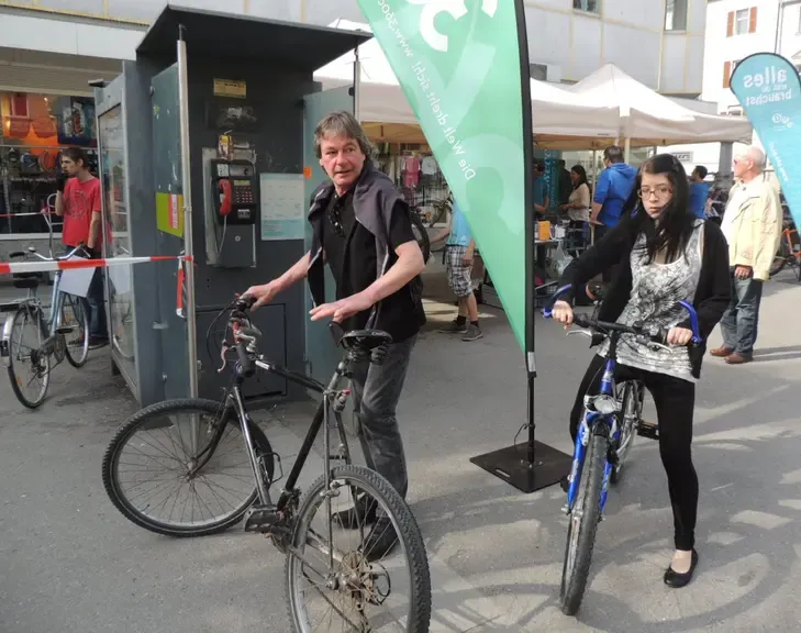 Mann und junge Frau mit Fahrrädern vor einer Telefonzelle in Österreich