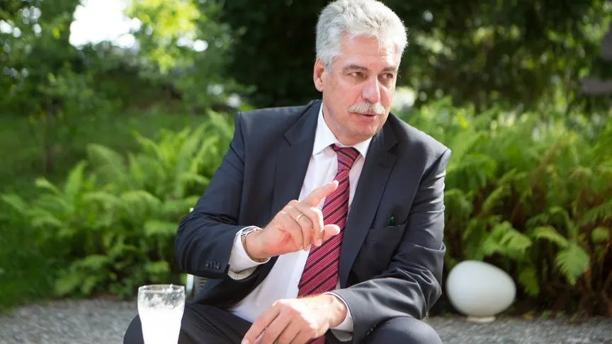 Hans-Peter Doskozil im Gespräch in einem Garten mit Farnen und einer weißen Lampe.
