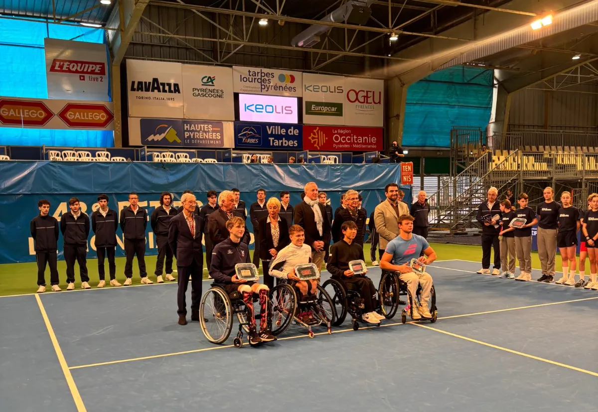 Tennisspieler in Rollstühlen und stehende Athleten mit Pokalen auf einem Tennisplatz in Tarbes.