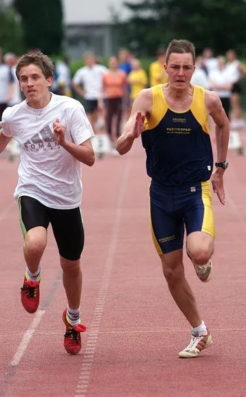 Leichtathletik-Wettkampf: Zwei Läufer auf einer Tartanbahn in voller Bewegung.
