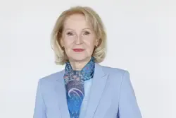 Elisabeth Köstinger, Politikerin, im Porträt vor weißem Hintergrund mit blauem Blazer und Halstuch.