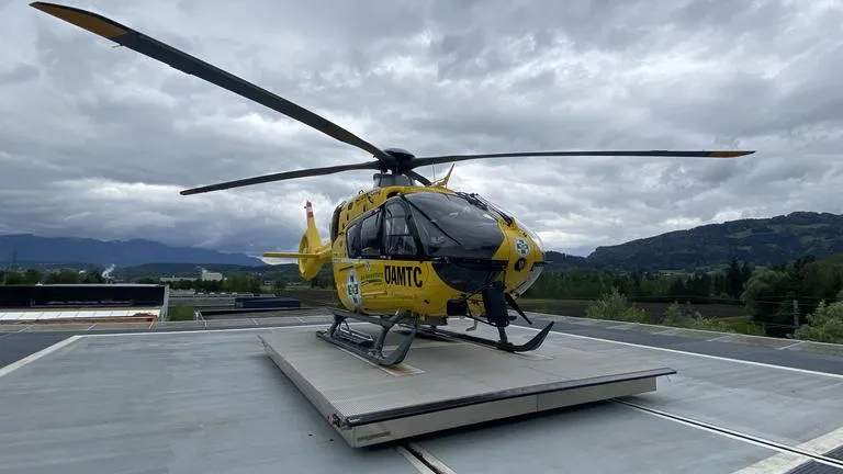RTH-Hubschrauber des ÖAMTC steht auf Landeplattform vor Bergkulisse