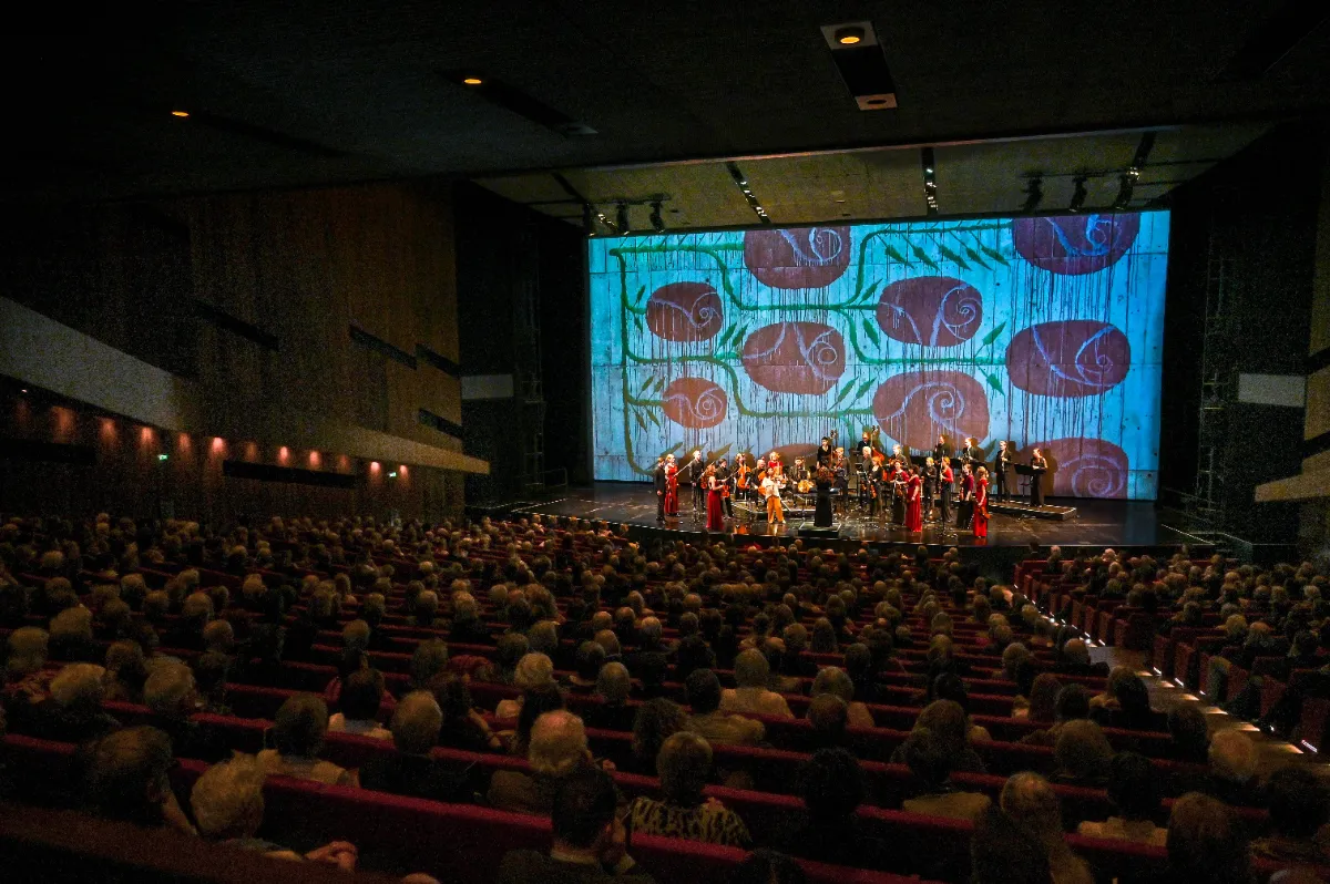 Orchester spielt vor Publikum im Theater mit Rosen-Projektion
