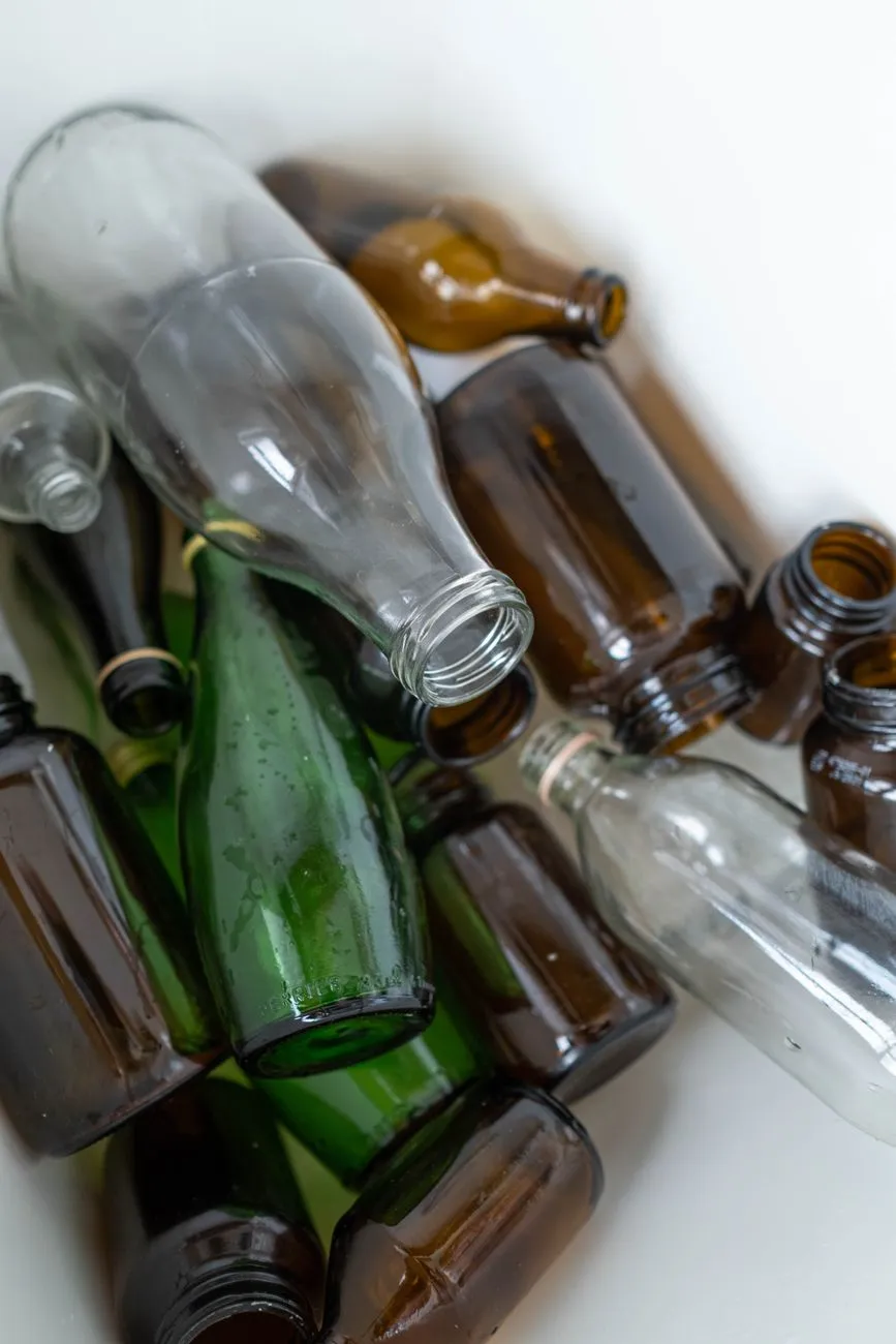 Glasflaschen, braune und grüne, liegen kreuz und quer in einem Behälter.
