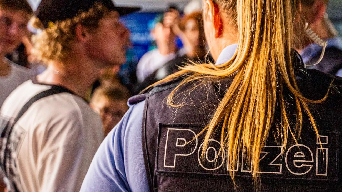 Polizistin mit Schriftzug "Polizei" auf der Weste im Gespräch mit einem Mann mit Kappe.