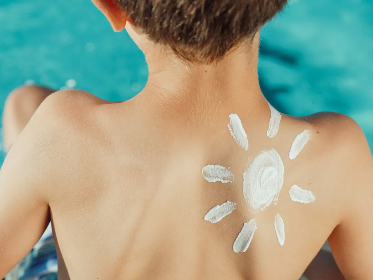Sonnenschutzmittel in Form einer Sonne auf dem Rücken eines Kindes am Pool