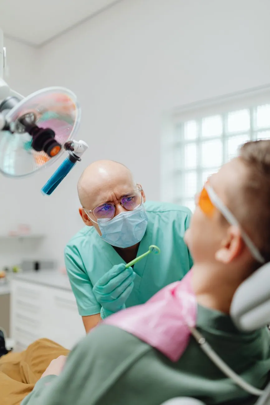 Zahnarzt mit Mundspiegel untersucht Patientin in Ordination