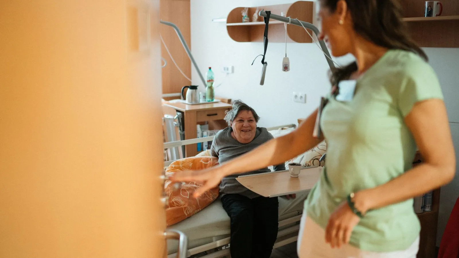 Pflegekraft hilft älterer Frau im Spital mit Essen und Trinken