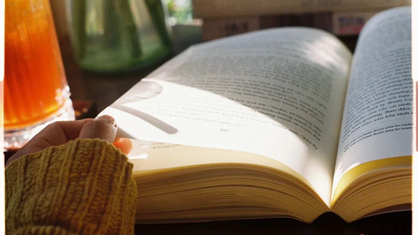 Buchseite mit Finger und Getränk im Hintergrund
