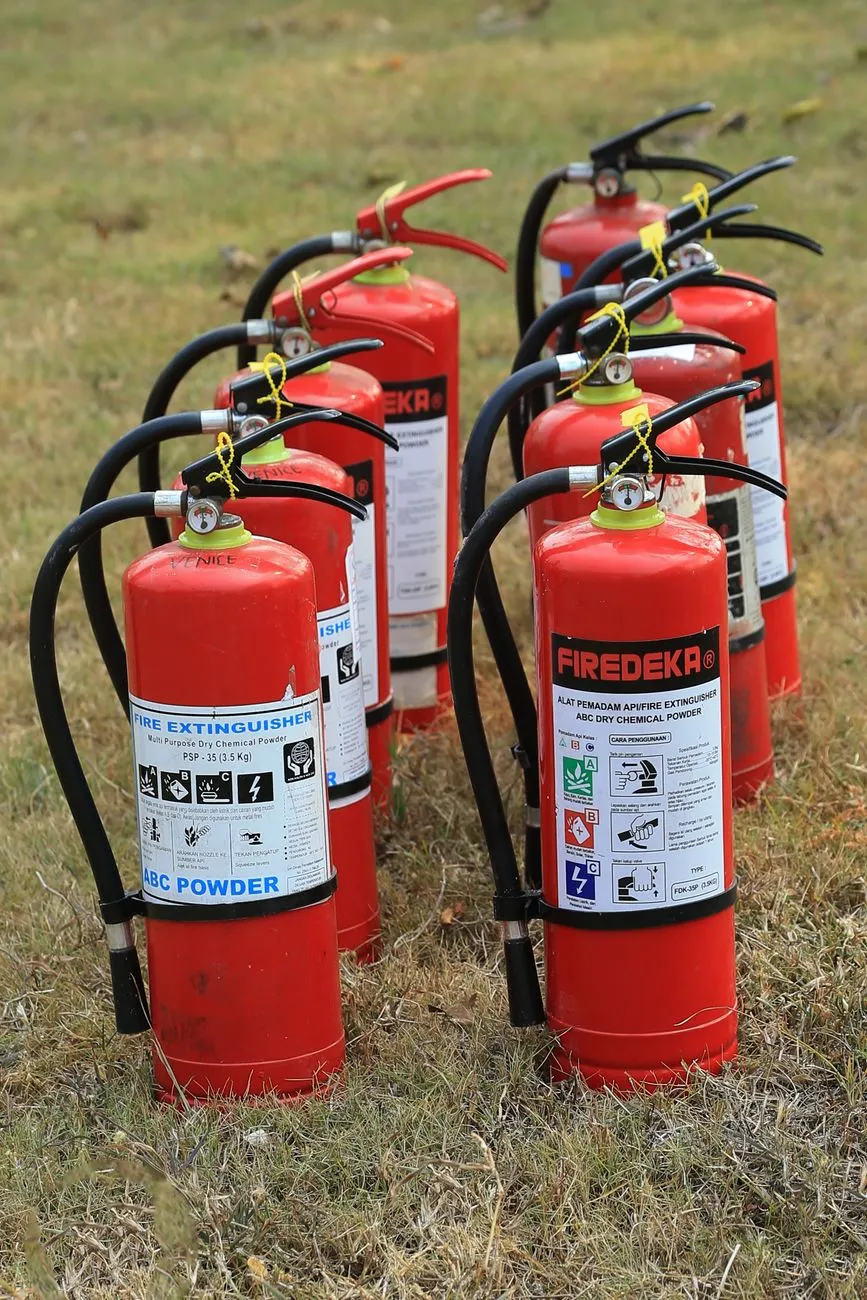 Feuerlöscher ABC Pulver in einer Reihe auf Gras aufgestellt