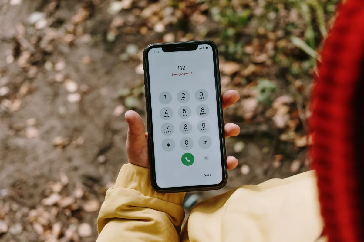 Notruf 112 auf einem Smartphone in der Hand einer Person mit gelber Jacke