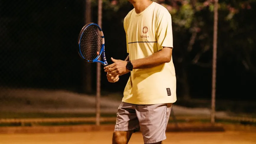 Tennisspieler mit Schläger auf Sandplatz bei Nacht