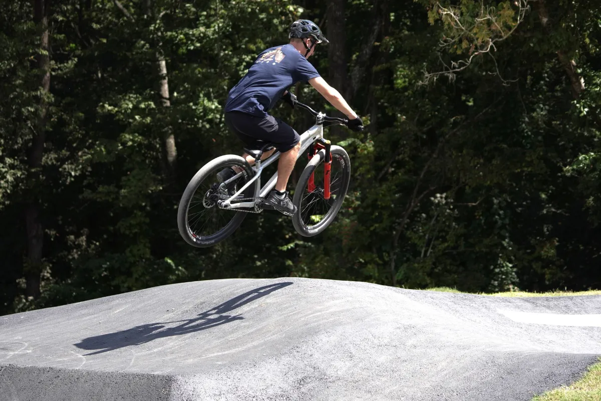 Mountainbiker springt mit seinem Radl über eine Rampe in einem Wald