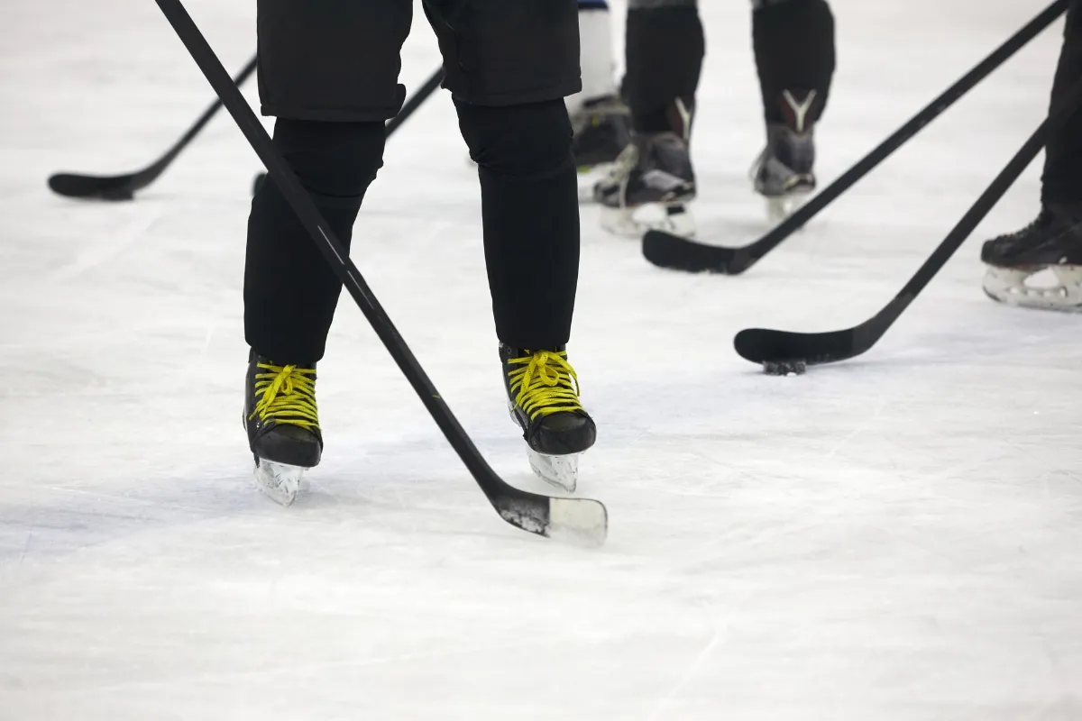 Eishockey-Spieler mit gelben Schnürsenkeln und Schlägern stehen auf Eis