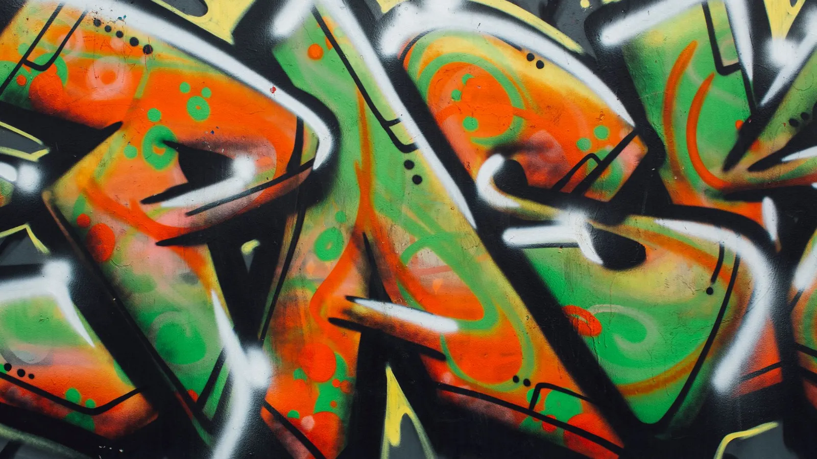 Graffiti in Orange, Grün und Schwarz mit Tupfen und Wirbeln