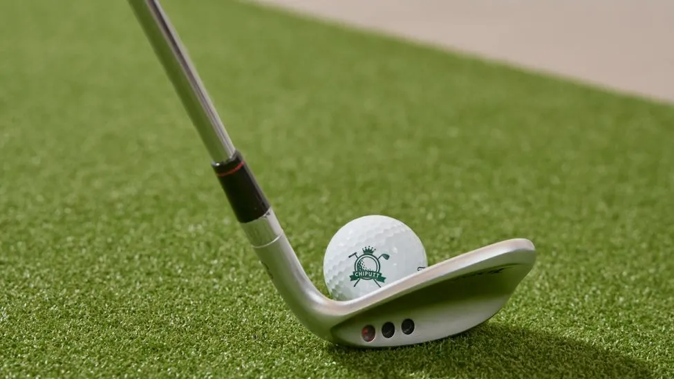 Golfschläger trifft Golfball auf Kunstrasen mit Logo "CHIPPUTT"