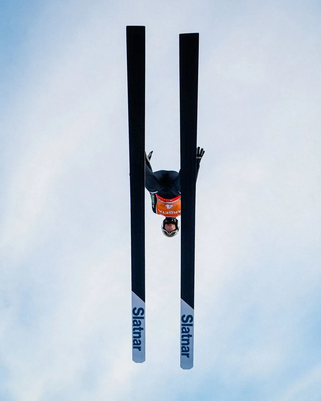 Skispringer im Flug über den Wolken mit Slatnar-Ski