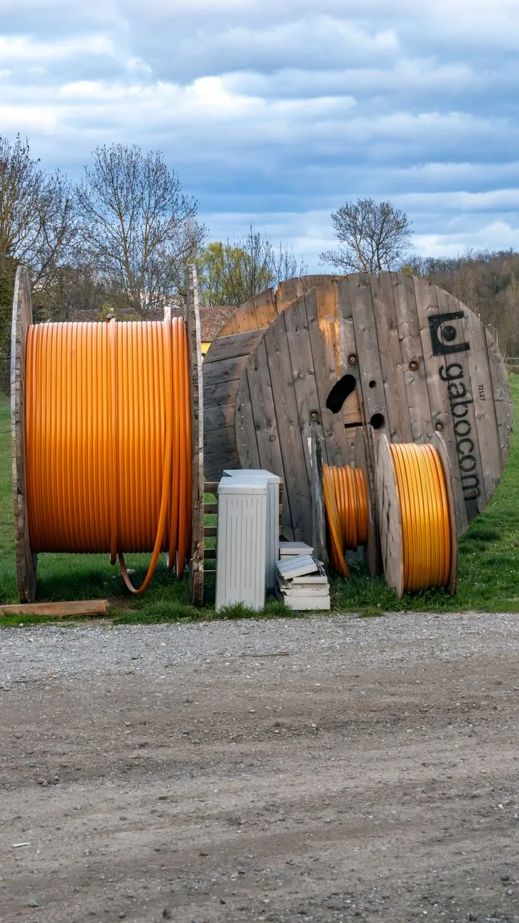 Kabeltrommeln mit orangefarbenen Kabeln und eine große Holzspule mit Gabocom-Logo stehen im Freien.