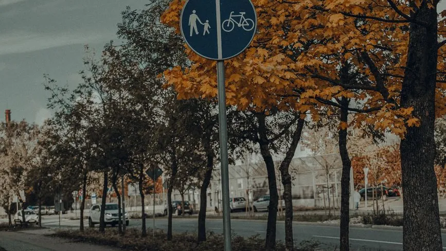 Radwegschild mit Fußgängern und Radfahrern im Herbst in Österreich