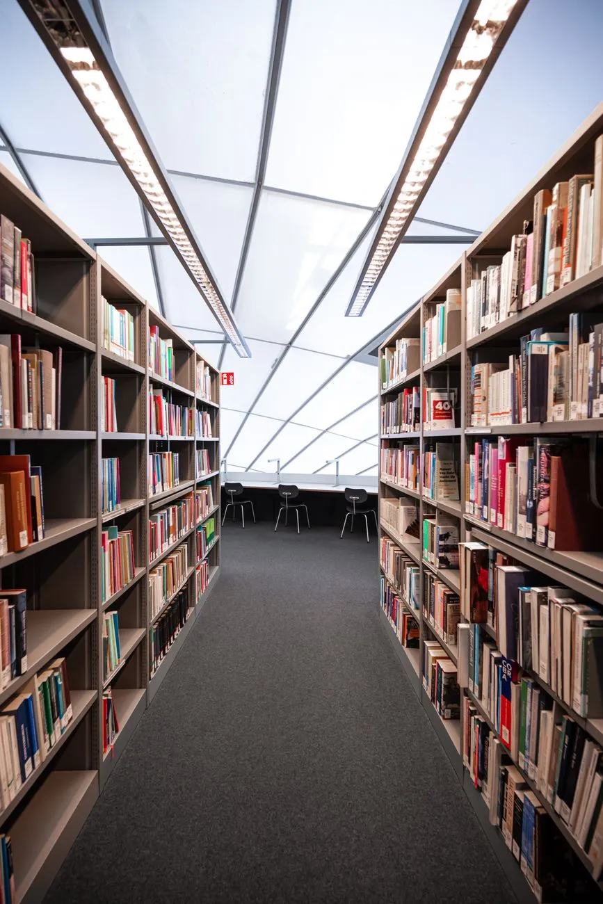 Bibliothek mit Bücherregalen und Lesetischen im Hintergrund, moderne Architektur mit Oberlicht