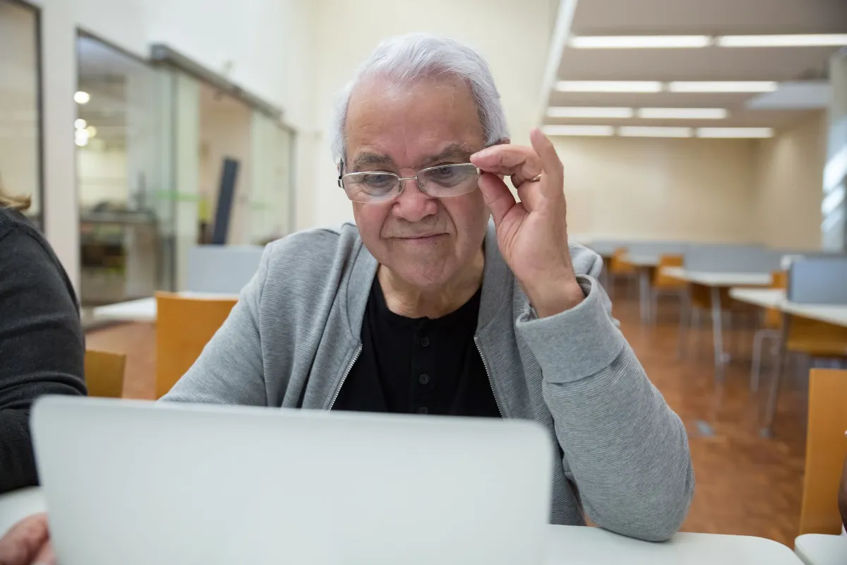 Senior mit Brille am Laptop in einem hellen Raum
