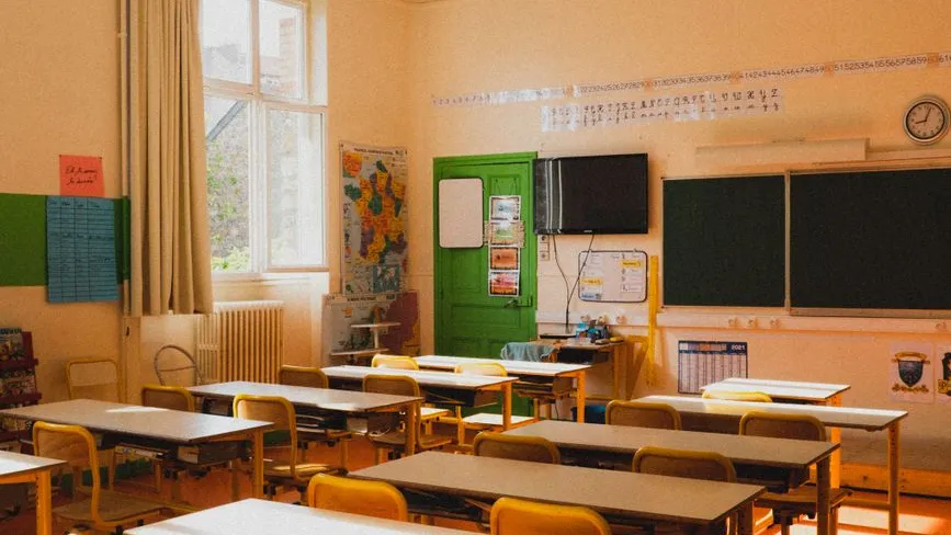 Klassenzimmer mit Schulbänken, Tafel und Landkarte an der Wand
