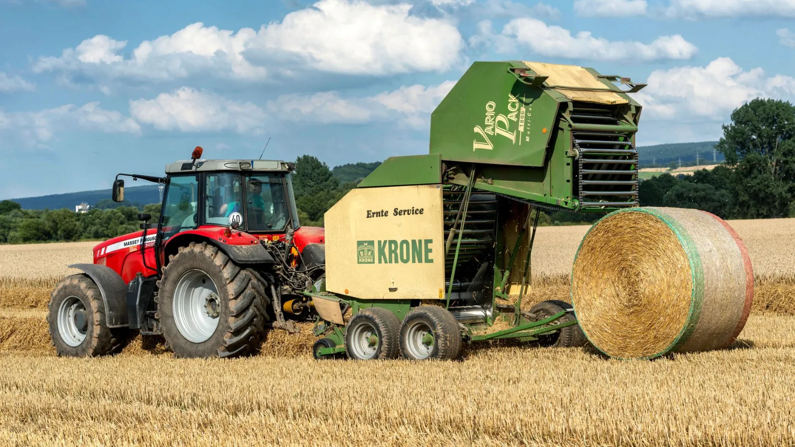 Ballenpresse KRONE mit Traktor Massey Ferguson bei der Ernte auf einem Feld in Österreich
