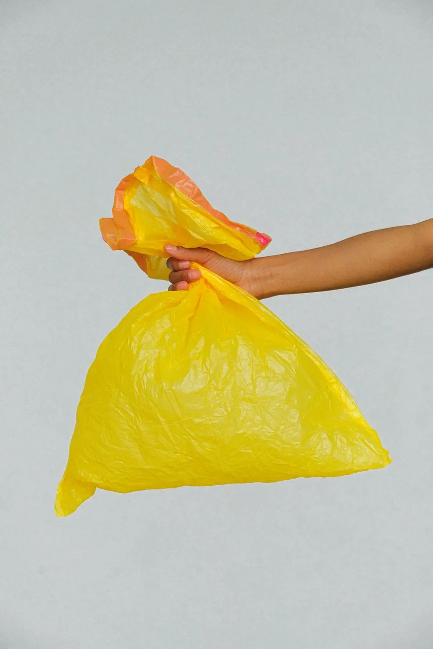 Gelbe Plastiktüte mit orangem Rand, gehalten von einer Hand