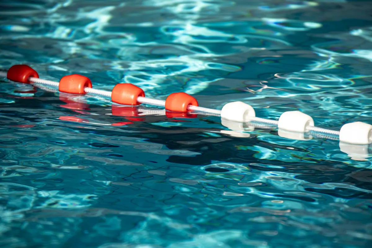 Schwimmbahnleinen mit roten und weißen Bojen im blauen Wasser eines Pools