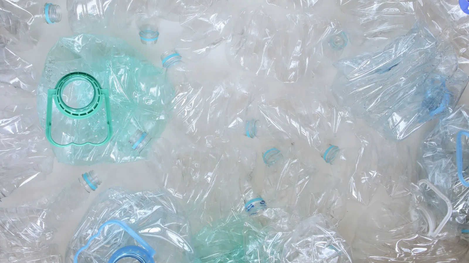 Leere PET-Flaschen und Wasserflaschen mit blauen und grünen Henkeln