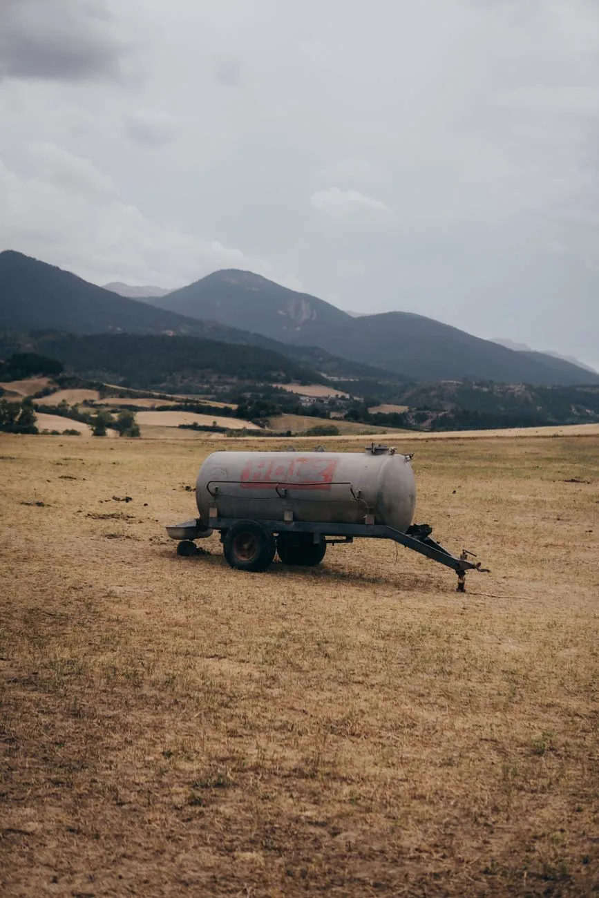 Güllefass auf trockenem Feld vor Bergkulisse in Österreich