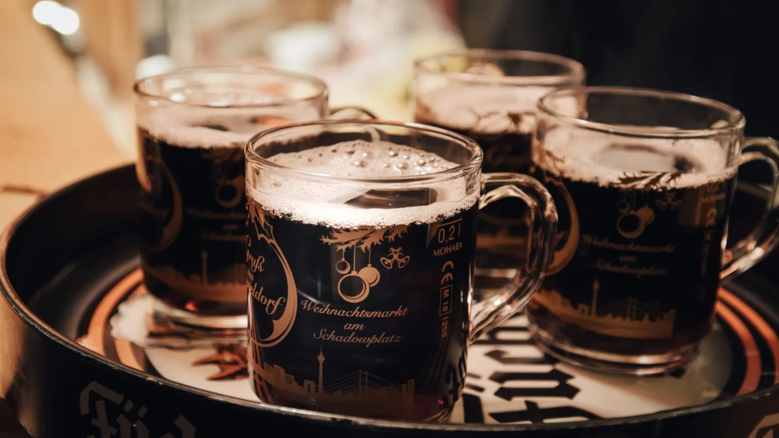 Glühwein am Weihnachtsmarkt am Schadowplatz in Düsseldorf, vier Tassen mit Schaum