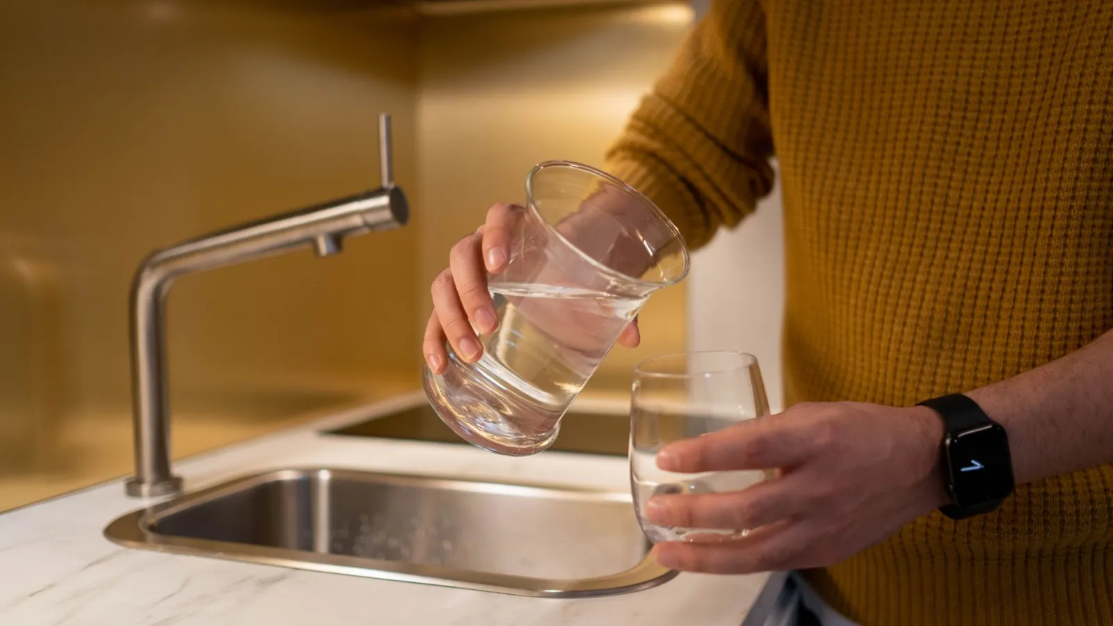 Wasser wird aus einem Glas in ein anderes in einer Küche in Wien gegossen.