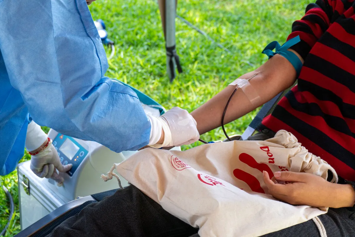 Blutspende: Eine Person im Schutzanzug entnimmt Blut aus dem Arm eines Spenders.