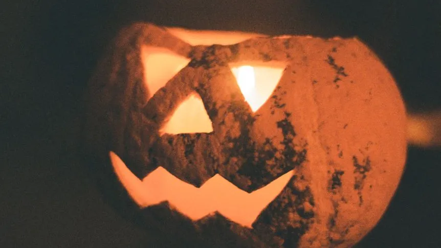 Halloween-Kürbis mit Kerzenlicht und gruseligem Gesicht im Dunkeln