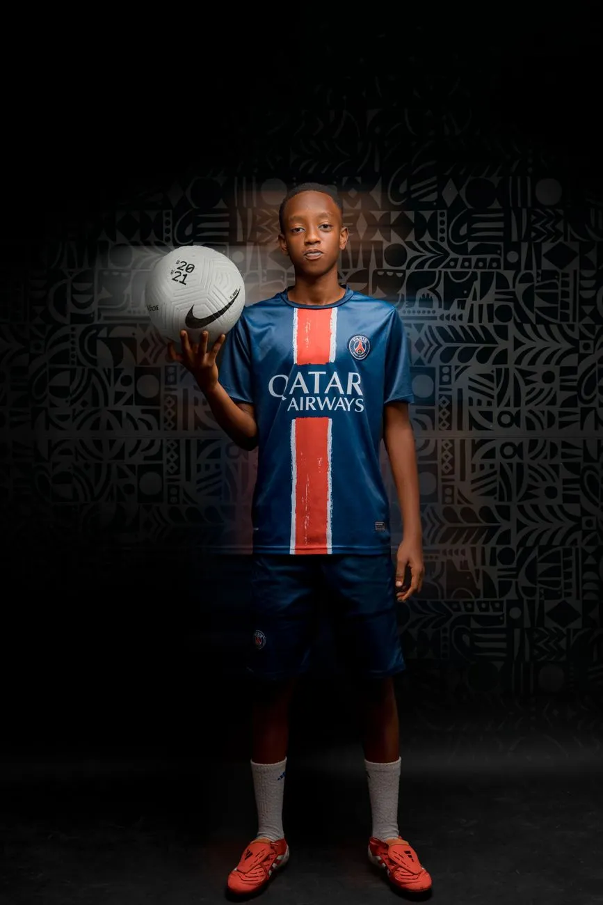 Fußballer mit Ball im Paris Saint-Germain Trikot vor dunklem Hintergrund