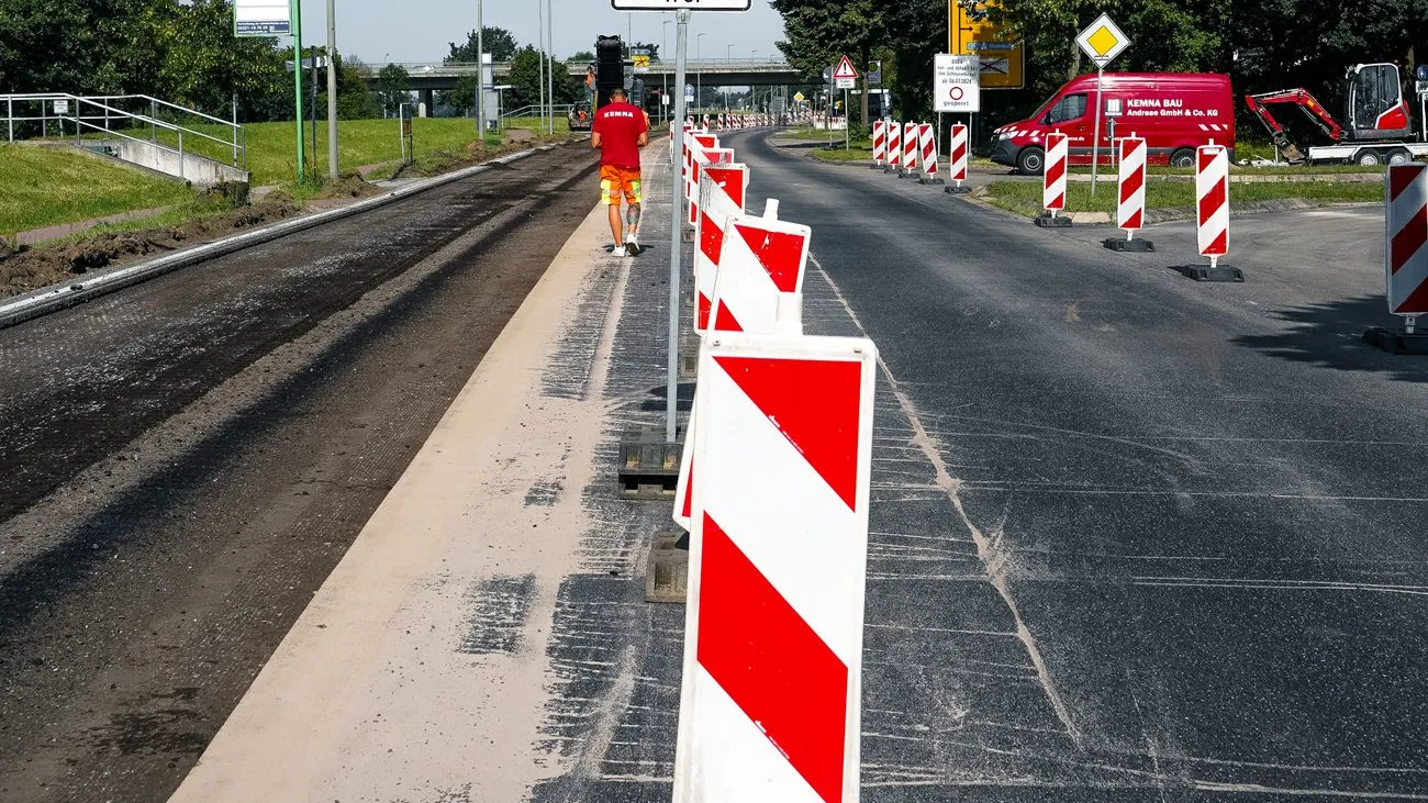 Straßenbauarbeiten mit Absperrungen und einem Arbeiter in rotem T-Shirt in Österreich