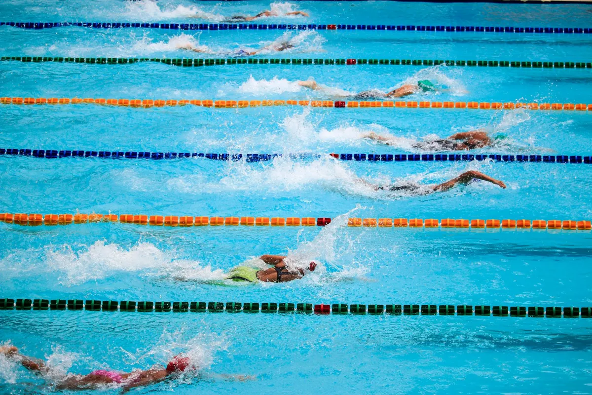 Schwimmer im Wettkampf in Bahnen, Wasser spritzt, Schwimmbecken