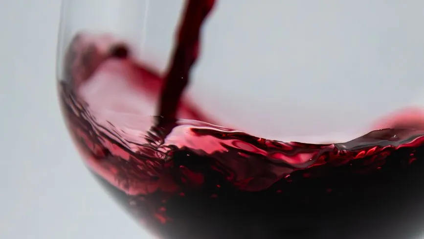 Rotwein wird in ein Weinglas gegossen, Nahaufnahme der Oberfläche
