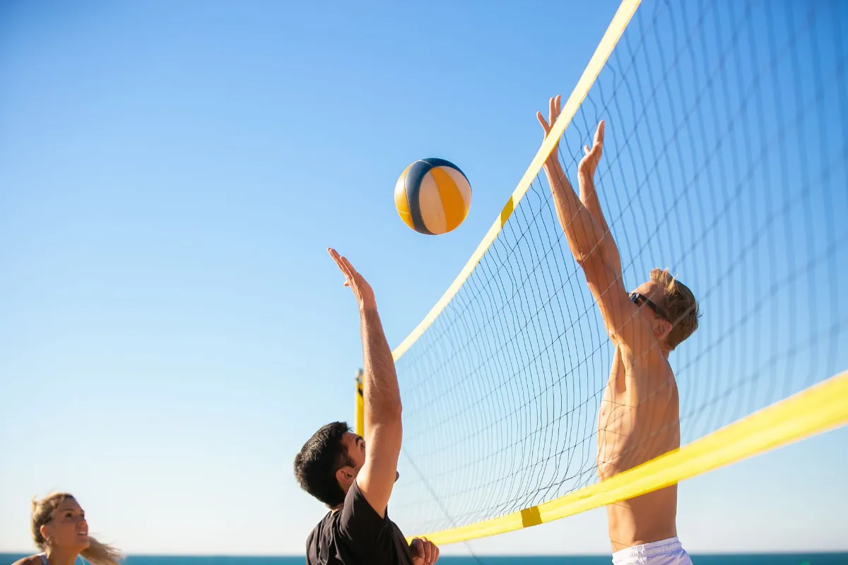 Beachvolleyball-Spieler am Netz mit Ball vor blauem Himmel