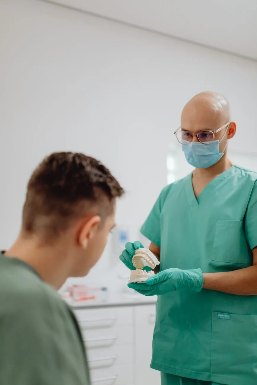 Zahnarzt erklärt einem Patienten ein Gebissmodell in einer Ordination in Wien