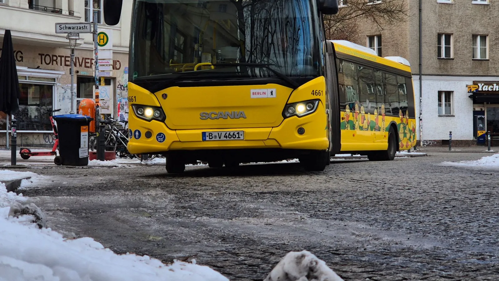 Gelber Linienbus der BVG in Berlin mit Werbung auf der Seite auf schneebedeckter Straße