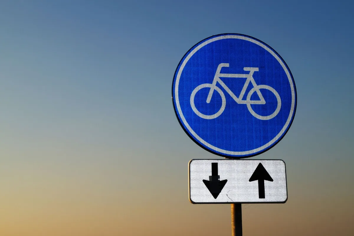 Radwegschild mit Pfeilen für Gegenverkehr vor blauem Himmel