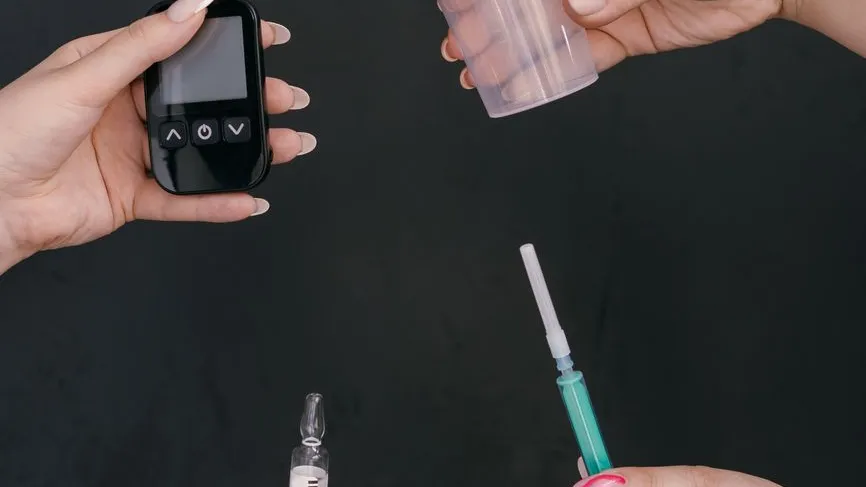 Blutzuckermessgerät, Spritze und Ampulle werden von Händen gehalten