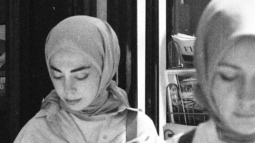 Junge Frau mit Kopftuch vor einem Regal mit Zeitschriften