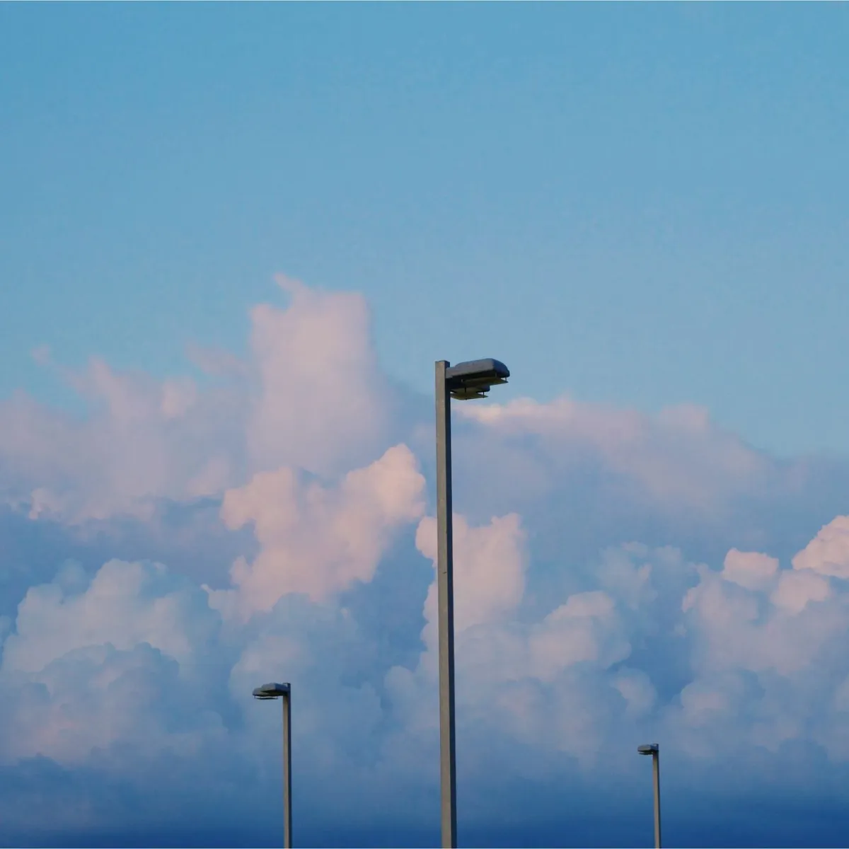 Straßenlaternen vor einer dramatischen Wolkenkulisse im Abendlicht