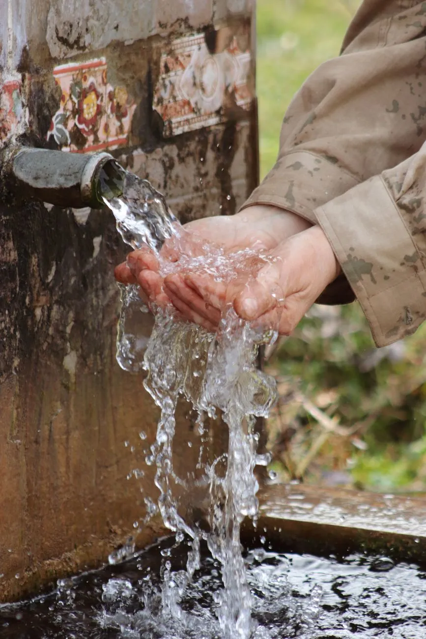 Hände unter fließendem Wasser aus einem Brunnen in der Steiermark.