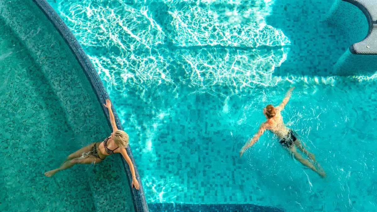 Frau und Mann entspannen im türkisfarbenen Pool in Österreich