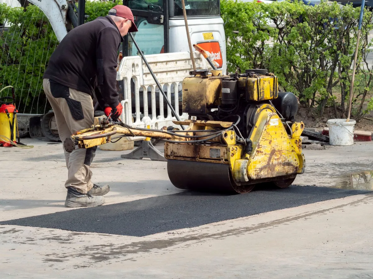 Straßenarbeiter verdichtet Asphalt mit einer Walze in Österreich